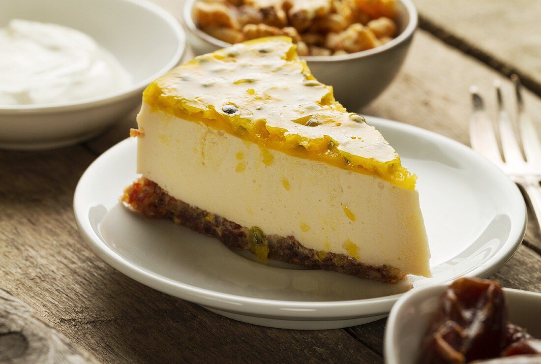 Ein Stück Cheesecake aus Mascarpone und griechischem Jogurt mit Maracuja, Kuchenboden aus Datteln und Walnüssen