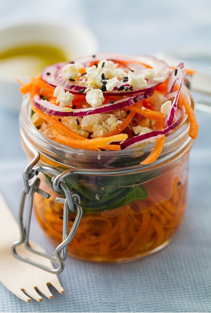Carrot salad with nuts, feta, spinach, red onions, olive oil and black sesame in a mason jar