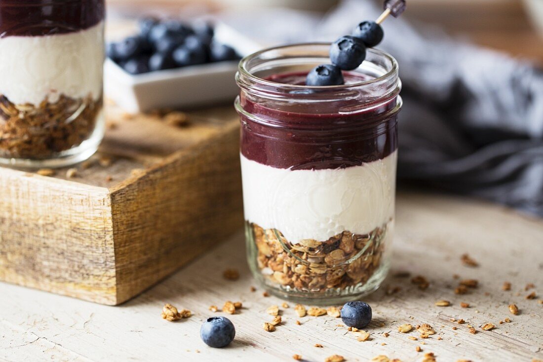 Schichtspeise aus Granola, Joghurt und Acai-Püree, garniert mit Blaubeeren