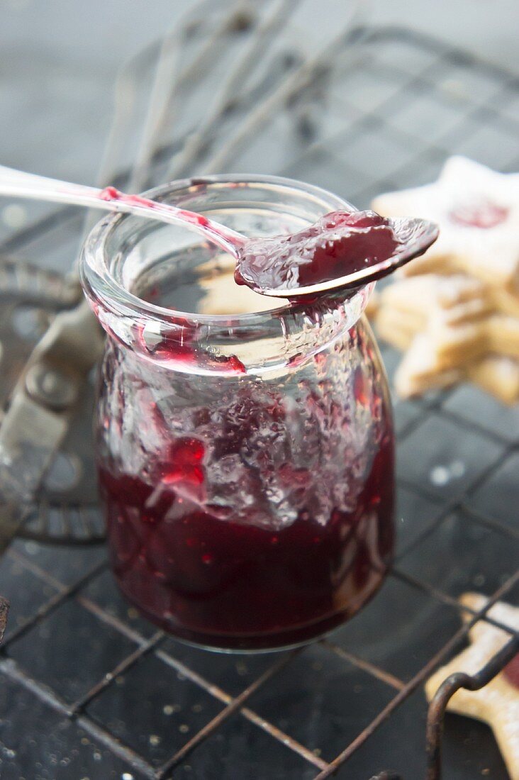 Currant jam in a jar with a spoon for filling jam biscuits