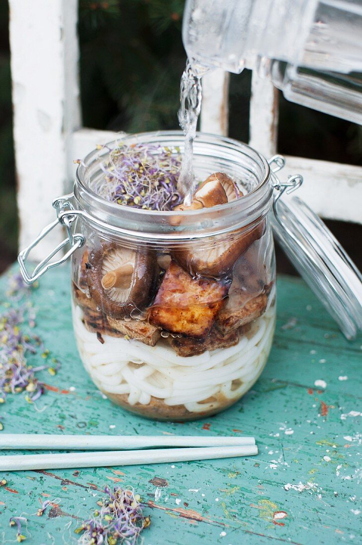 Miso soup in a glass jar with miso paste, Udon noodles, fried Teriyaki tofu, Shiitake mushrooms and sprouts