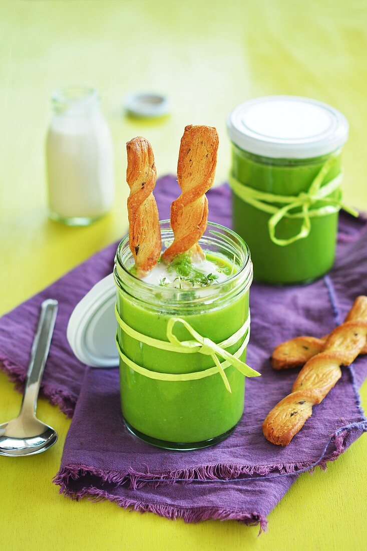 Creamy pea soup in glasses with pastry sticks