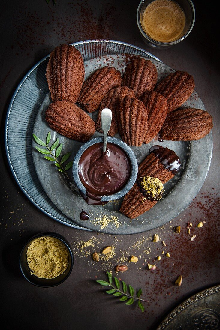 Chocolate madeleines with a chocolate sauce and pistachio crumbs (top view)