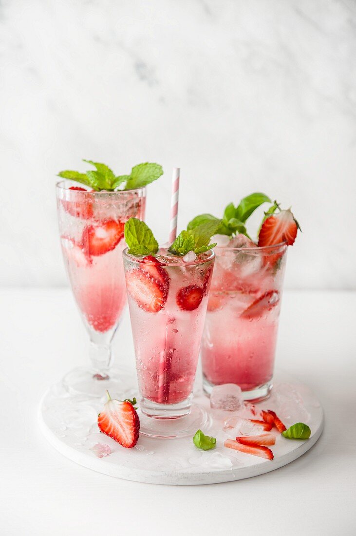 Erdbeer-Fizz mit frischen Erdbeeren, Minze und Basilikum in drei Gläsern
