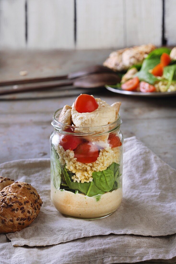 Layered salad in a glass with yellow pea cream, spinach and tomatoes