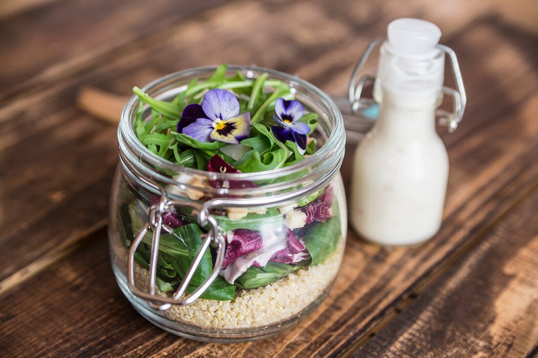 Quinoasalat mit Feldsalat, Radicchio, Rucola, Croûtons, Ziegenkäse und Hornveilchen im Glas, Dressing