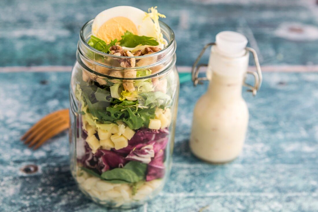 Orzosalat mit Feldsalat, Radicchio, Frisee, Croûtons, Käse, Walnüssen und Ei im Glas, Dressing, Holzgabel