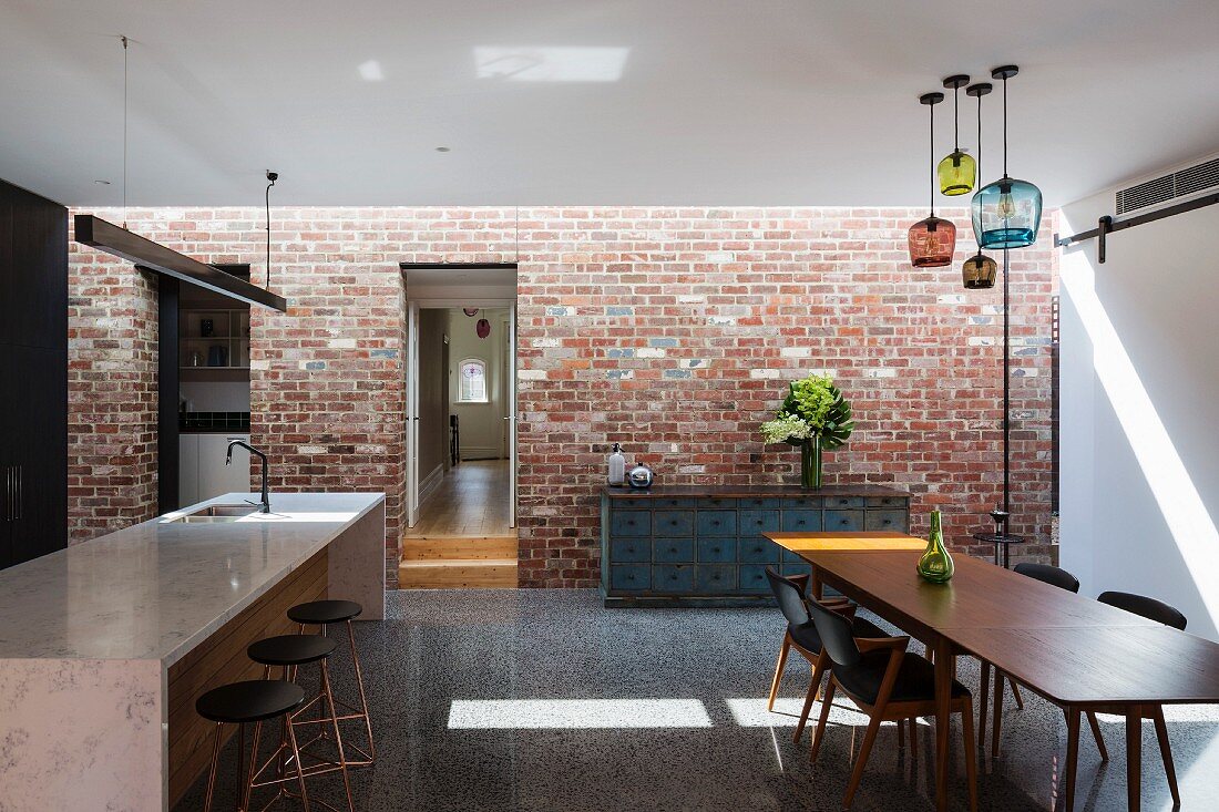 Industrial-style kitchen and dining room with brick wall
