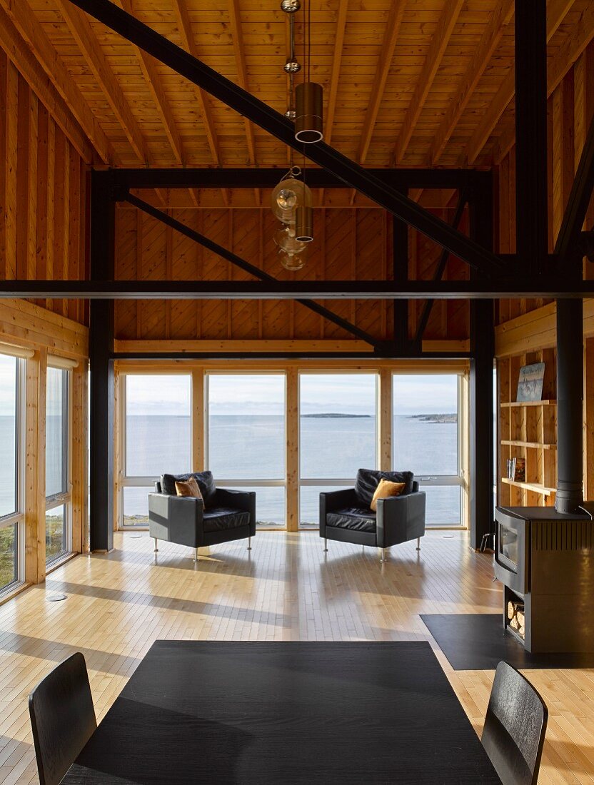 Modernes Holzhaus mit Fensterfront und schwarzen Balken und Möbeln