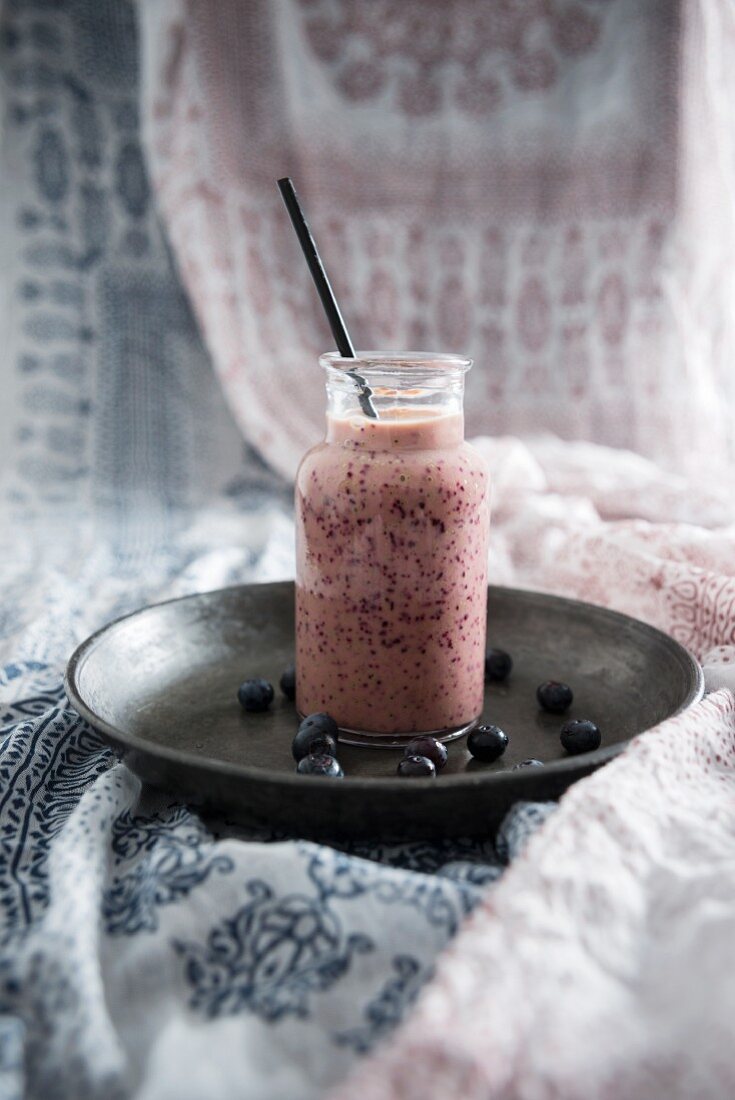 A vegan blueberry and yoghurt smoothie in a glass jar