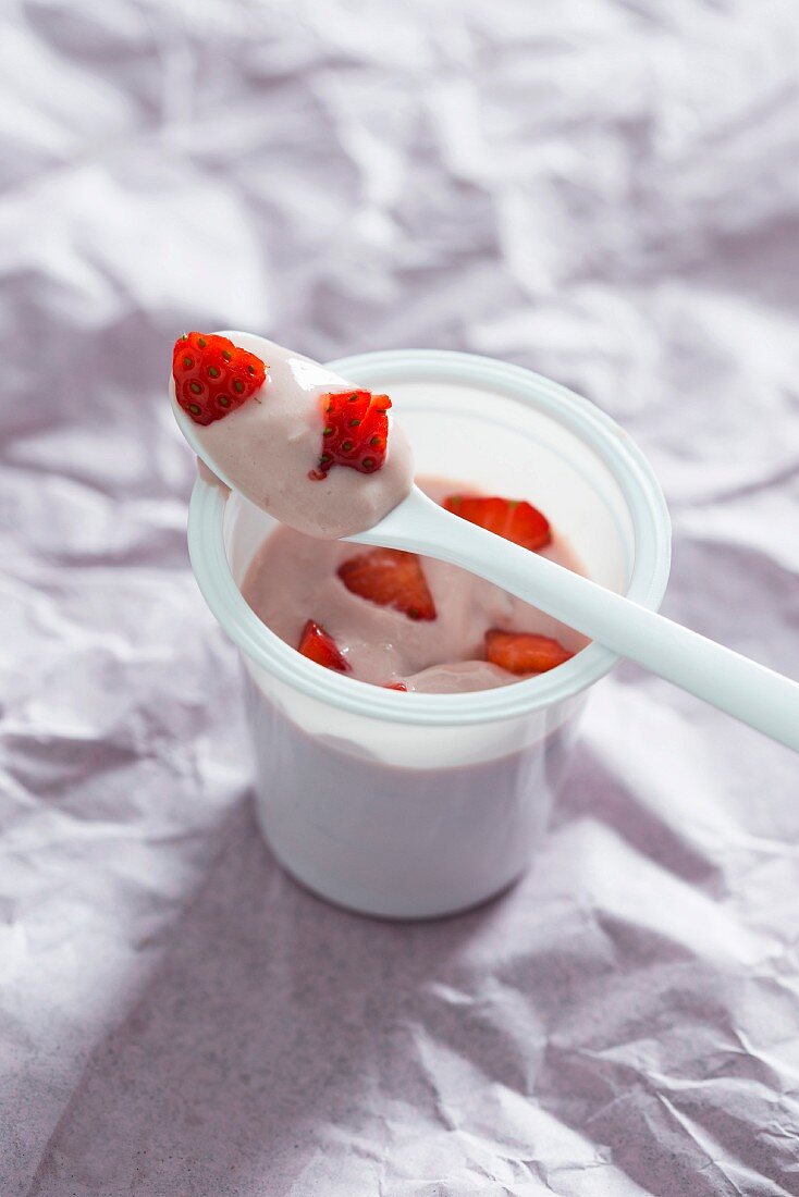 Sojajoghurt im Plastikbecher mit frischen Erdbeeren (vegan)