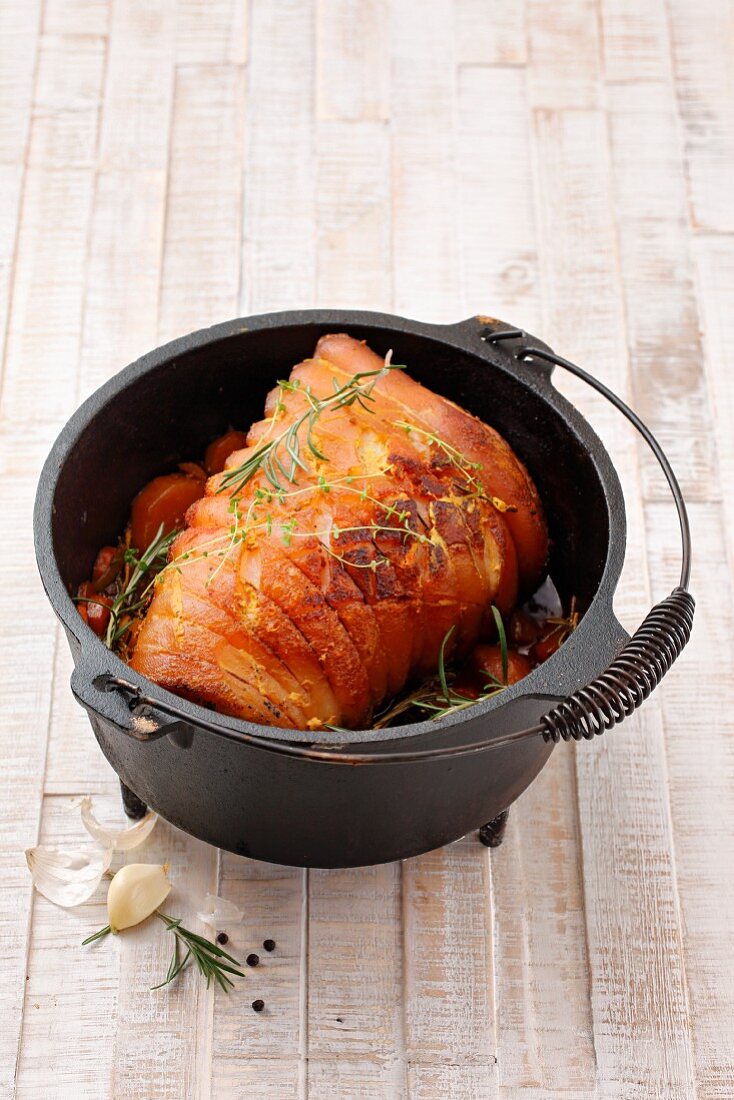 Rolled roasted pork belly in a Dutch oven cooking pot