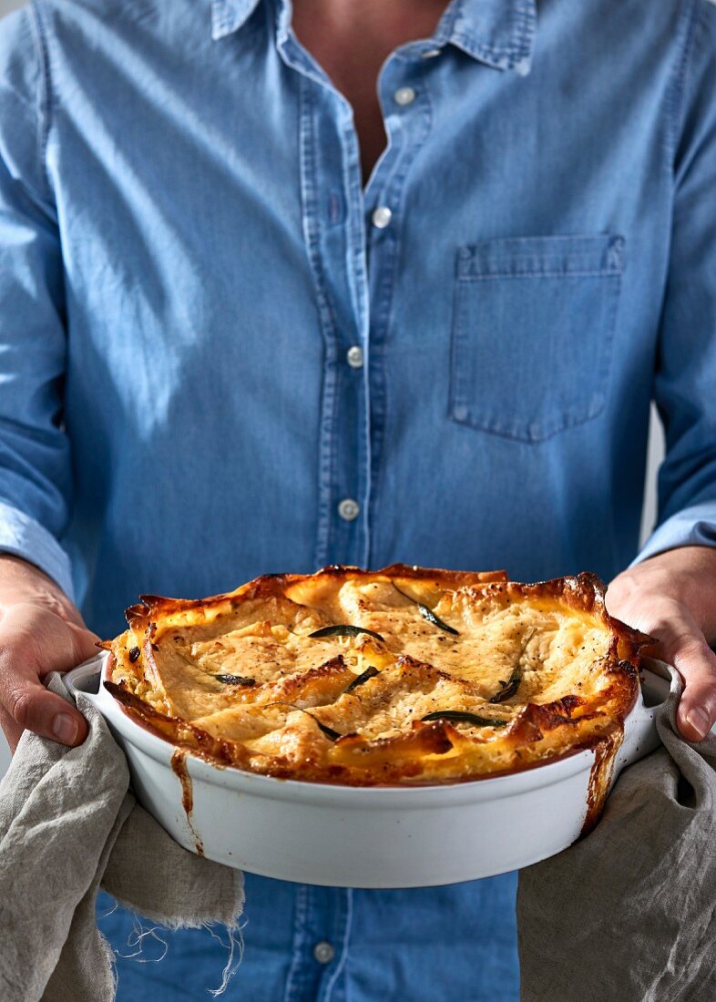 Mann hält Lasagne frisch aus dem Ofen