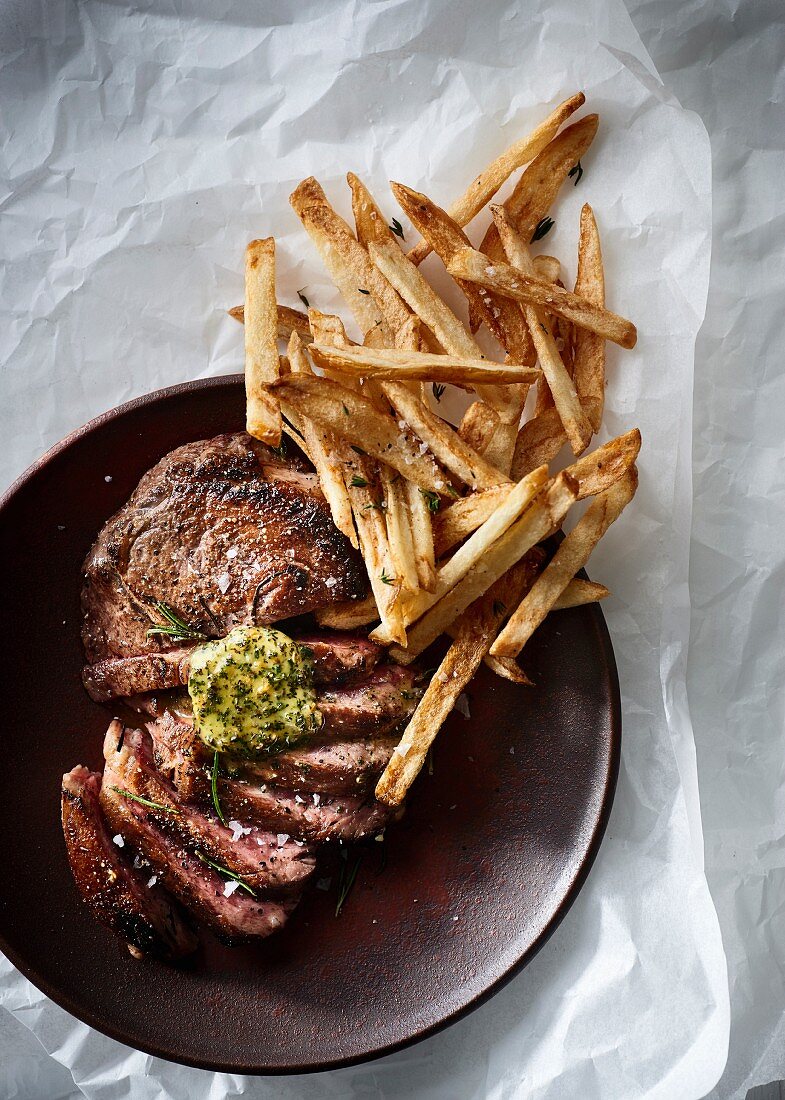 Sliced ribeye steak with herb butter and thin french fries