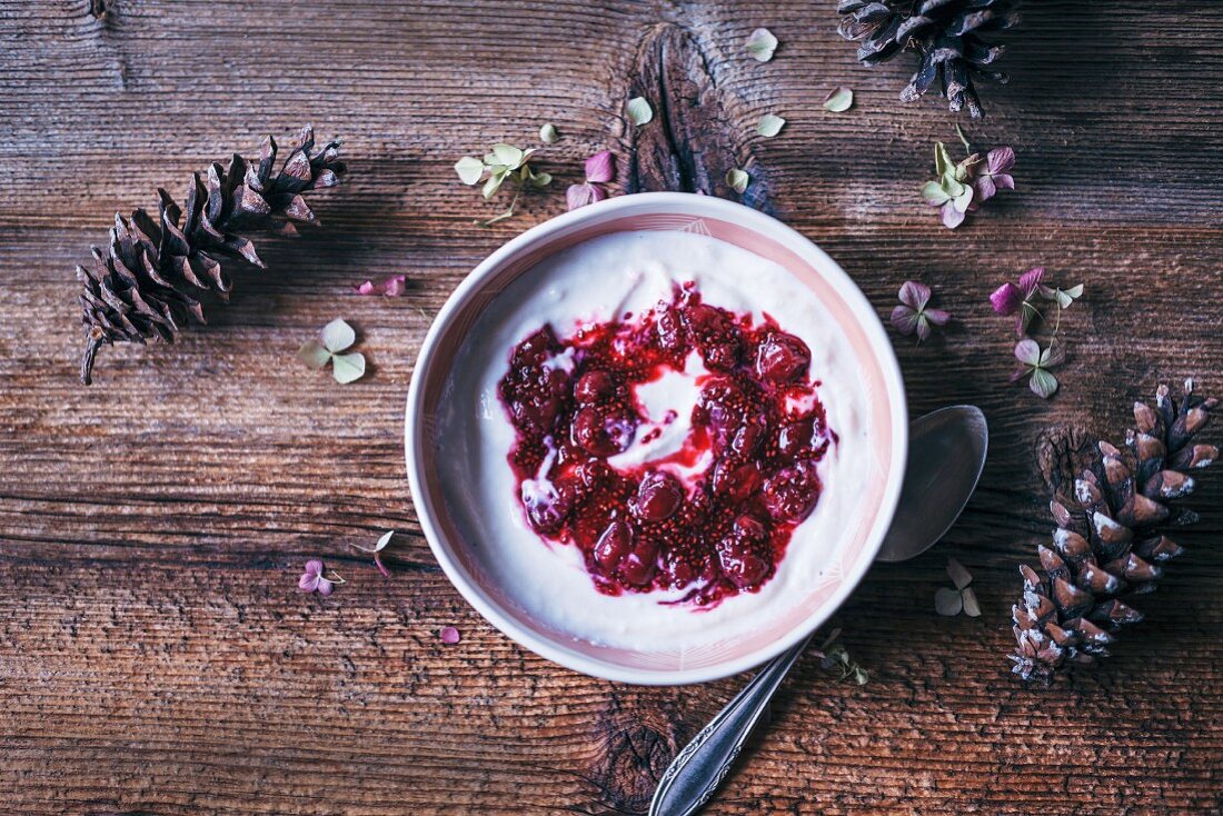 Ein Schälchen Joghurt mit Sauerkirschmarmelade auf Holzuntergrund