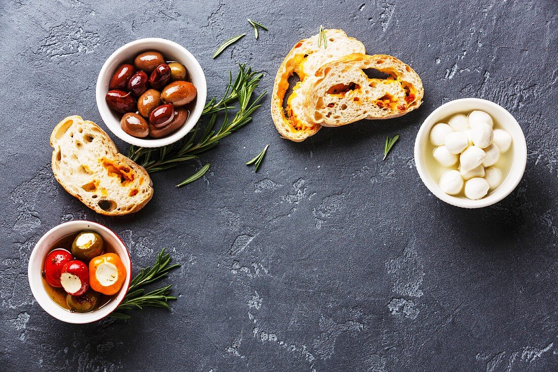 Antipasti: Oliven, gefüllte Paprika, Mini-Mozzarella und Ciabatta (Aufsicht)
