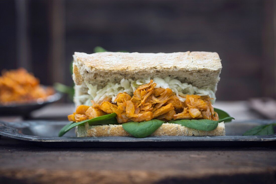 A vegan shredded jackfruit sandwich with spinach and cabbage