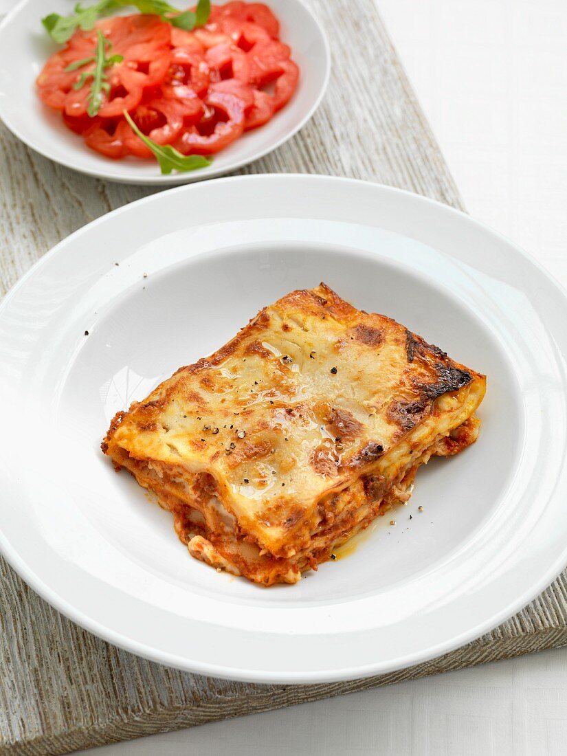 A portion of lasagne with a tomato salad