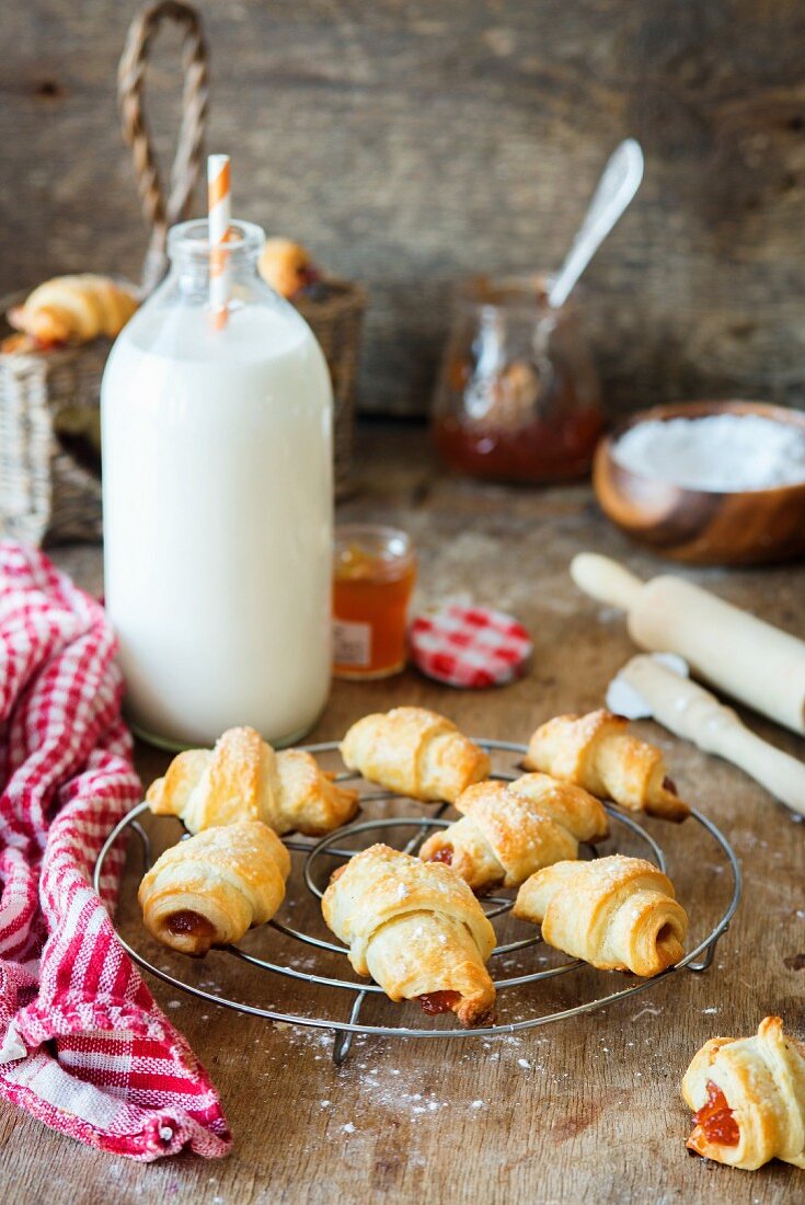 Croissants with jam on a cooling tray in front of a milk bottle