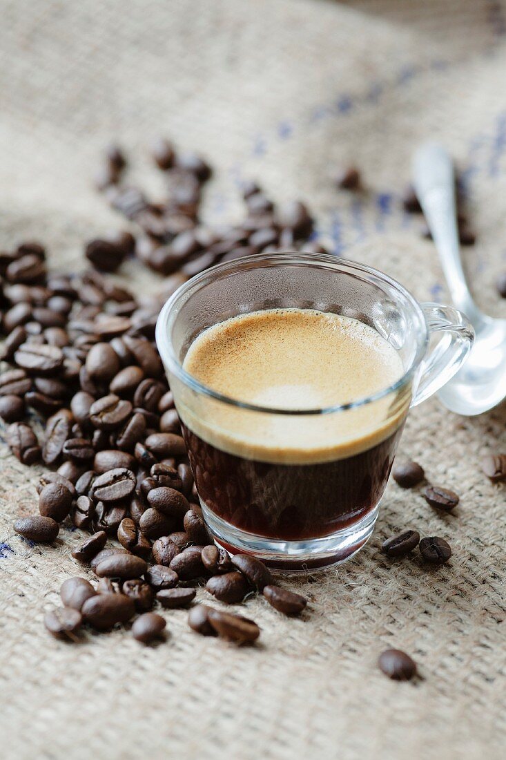 Espresso im Glas, Kaffeebohnen und Kaffeelöffel