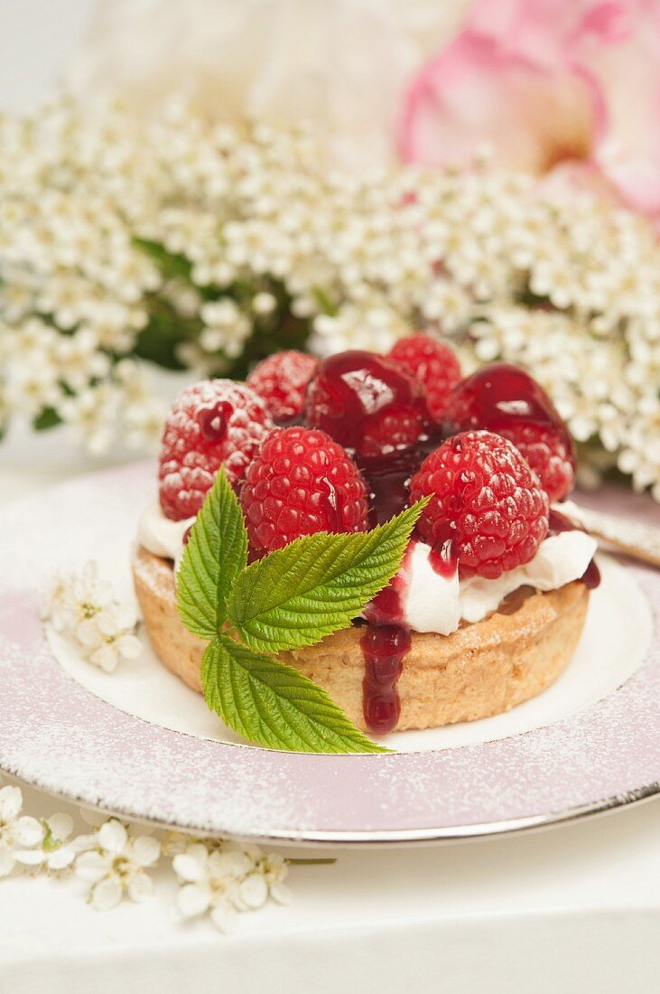 A fresh rasberry tart with a rasberry leaf with rose and hawthorn flowers