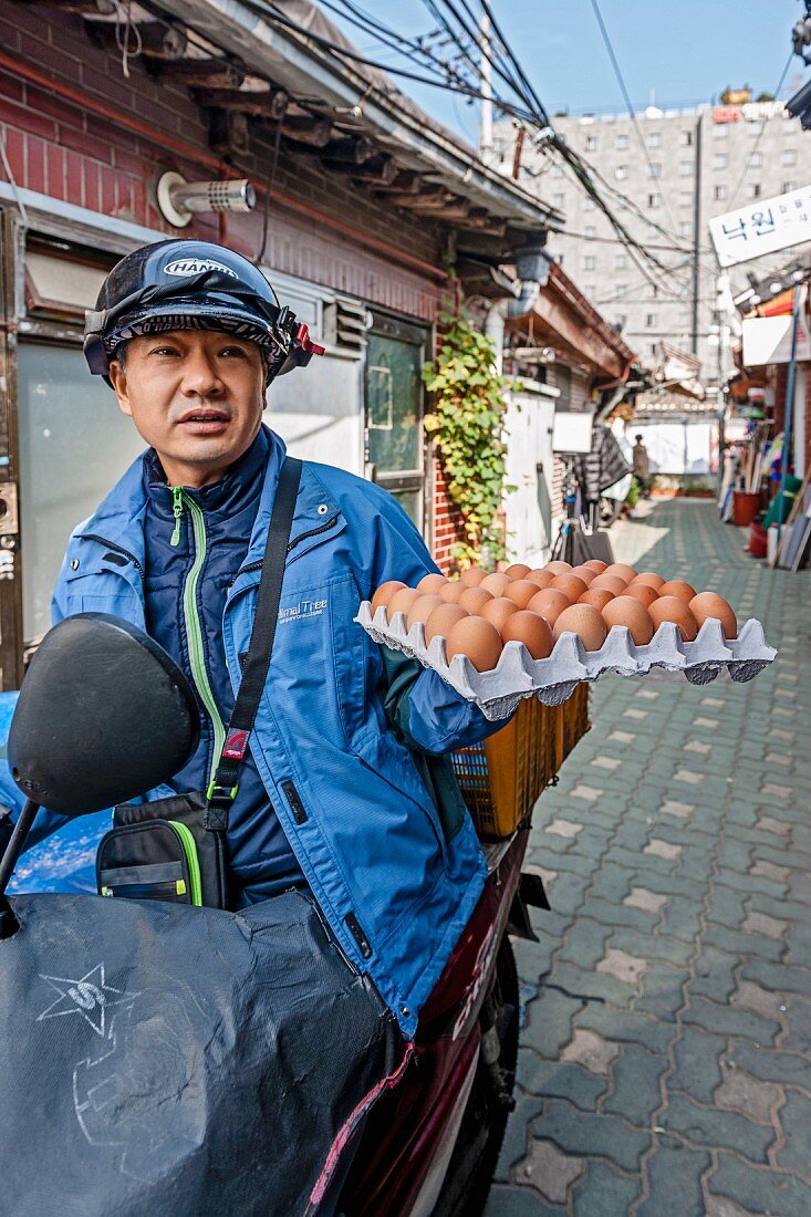 A moped driver with a box of eggs in Seoul, South Korea