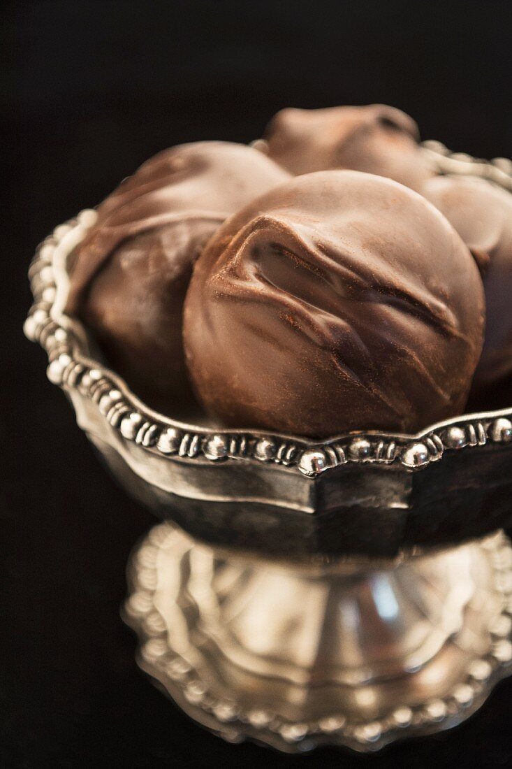 Schokoladenkonfekt mit Macadamianüssen in Silberschale (Nahaufnahme)