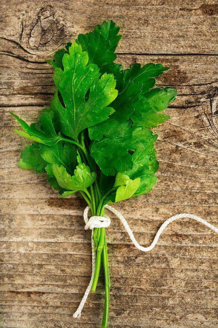 A bunch of smooth parsley on a wooden background (top view)