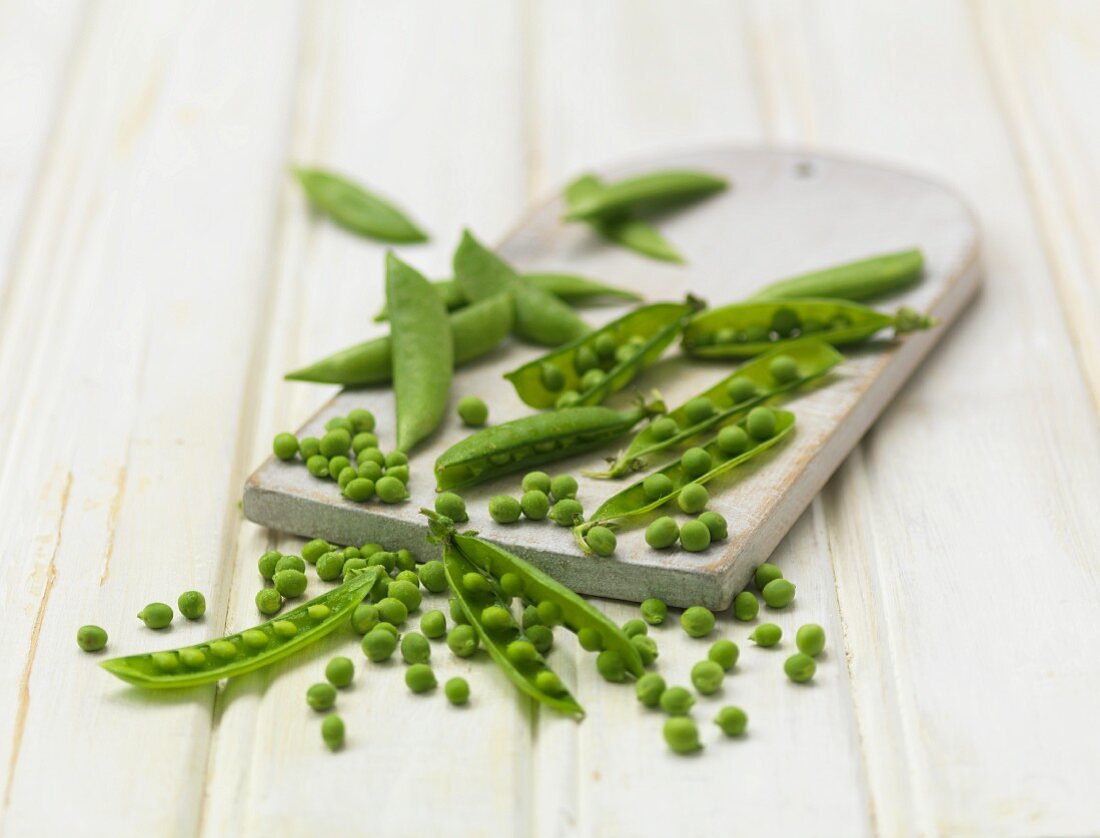 Peas and pea pods on a chopping board