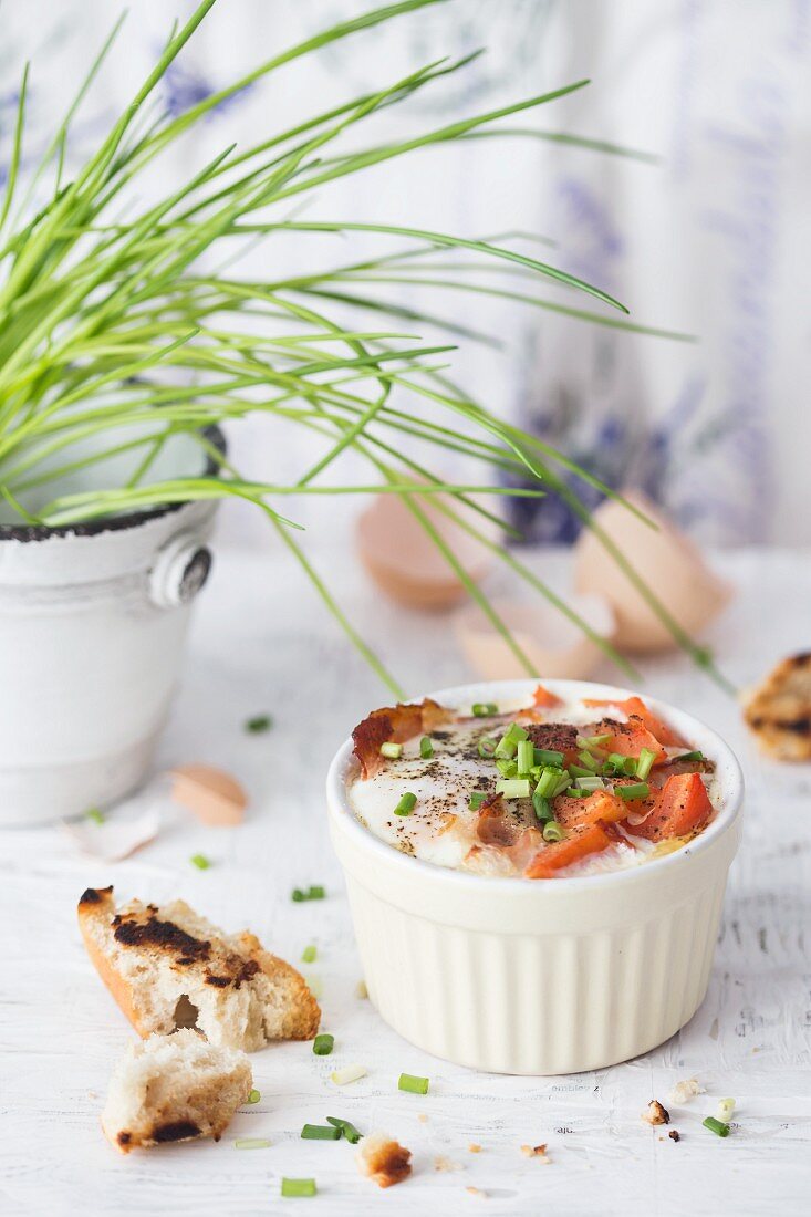 Baked eggs with bacon, tomatoes and chives