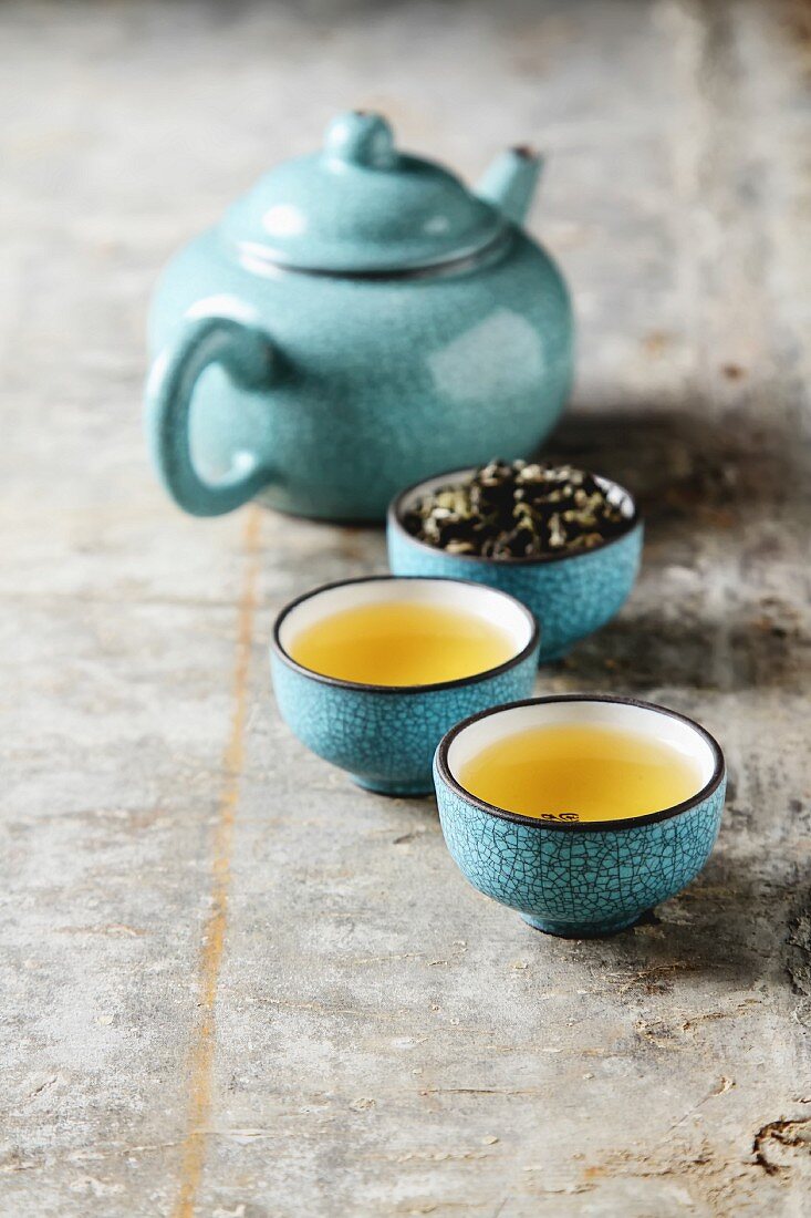 Tee in Porzellanschalen, Teeblätter und Teekanne (Asien)