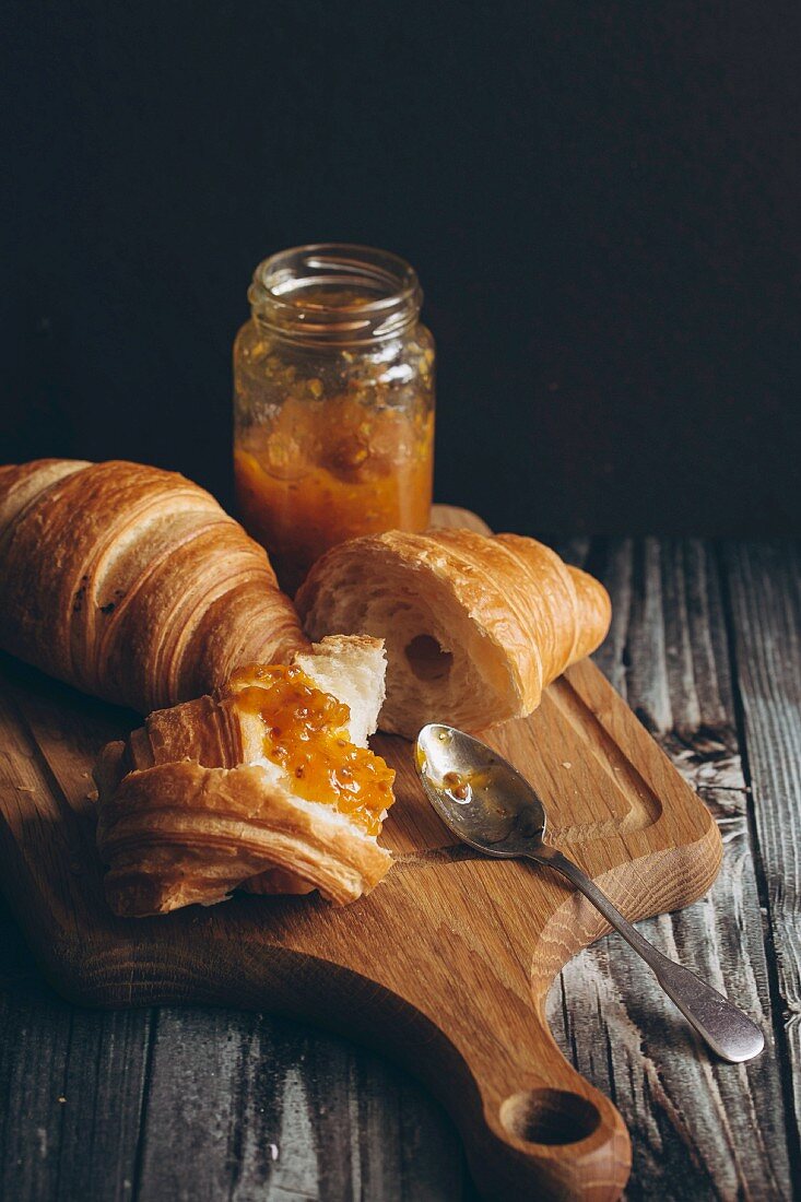 Croissants and marmalade on a chopping board