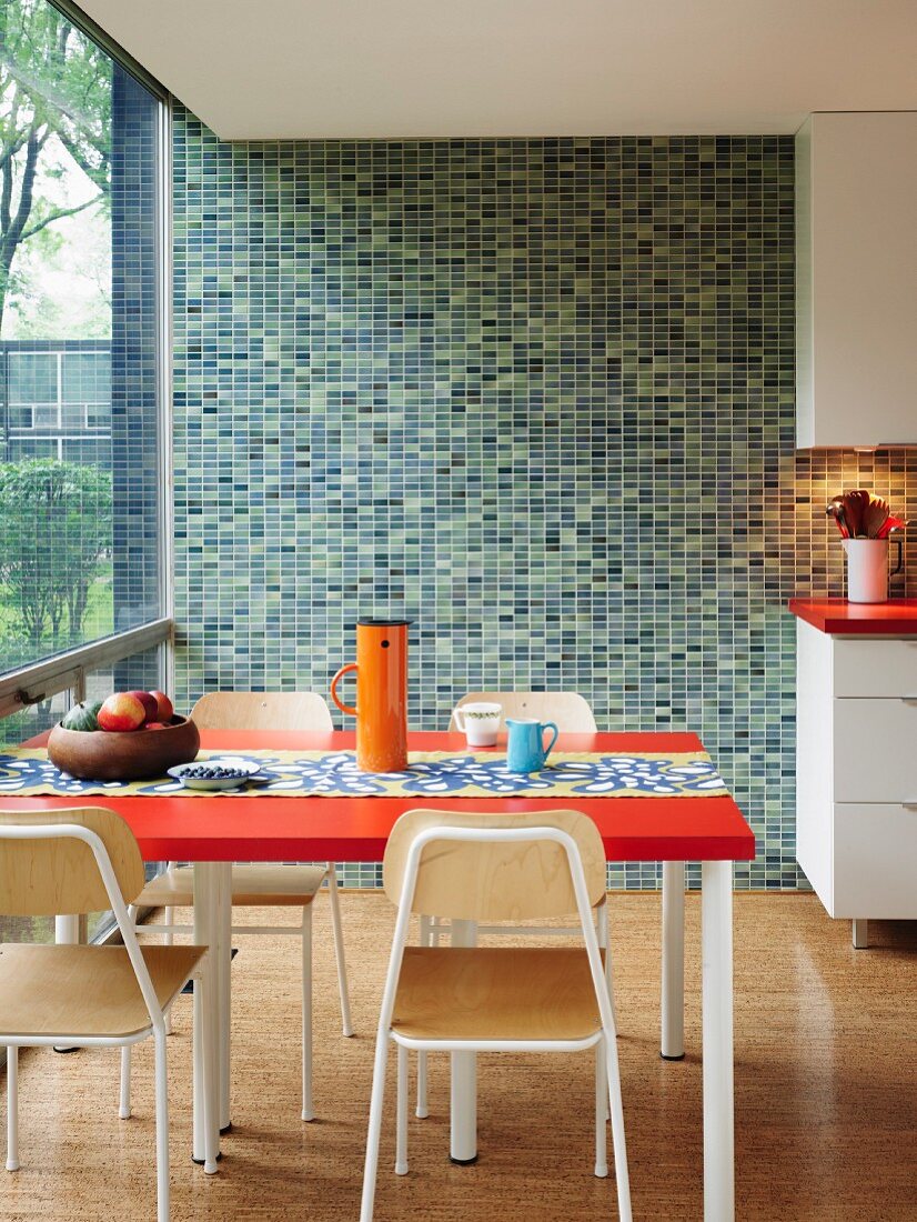 Mosaic wall in various shades of green in retro kitchen with glass wall