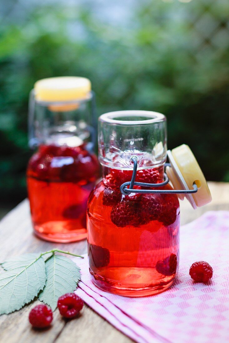 Homemade raspberry vinegar in flip-top bottles on a table outdoors