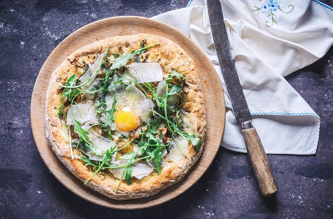 A pizza with rocket, fried egg and parmesan (seen from above)