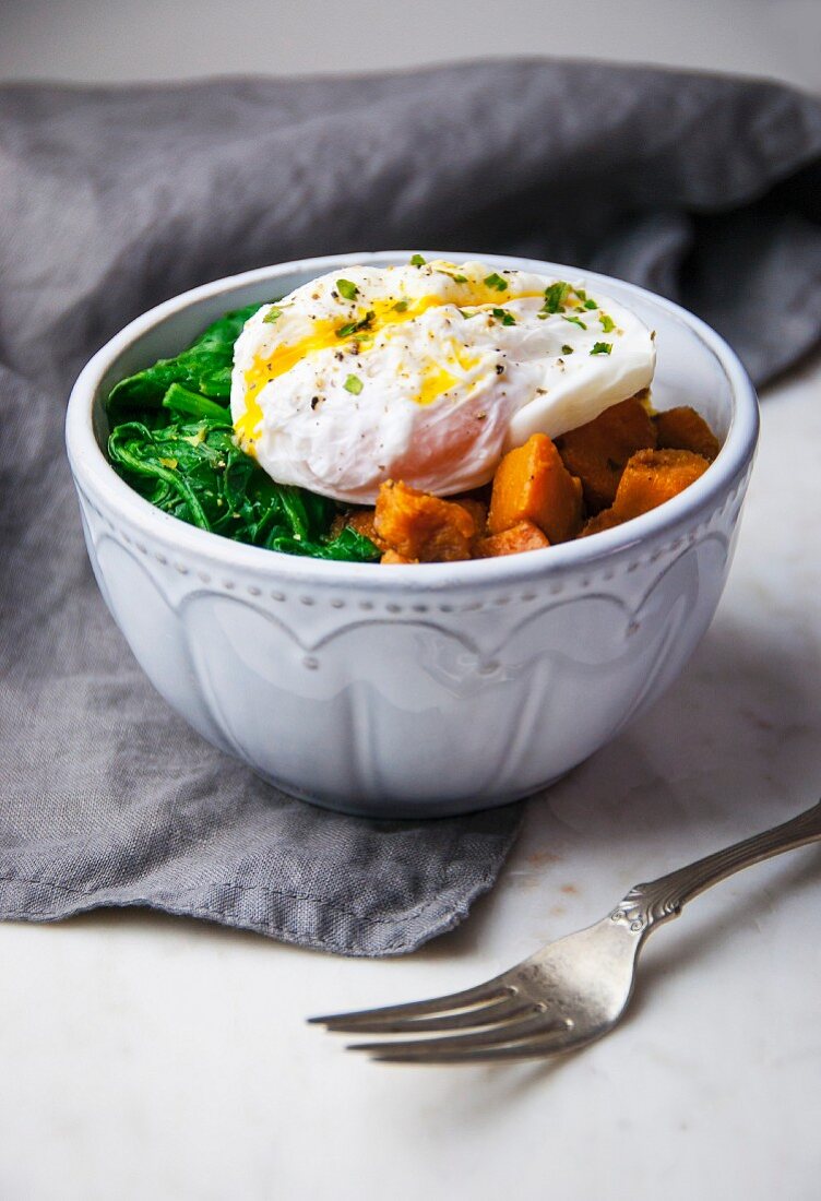 A breakfast bowl with poached egg, sauteed greens and sweet potatoes