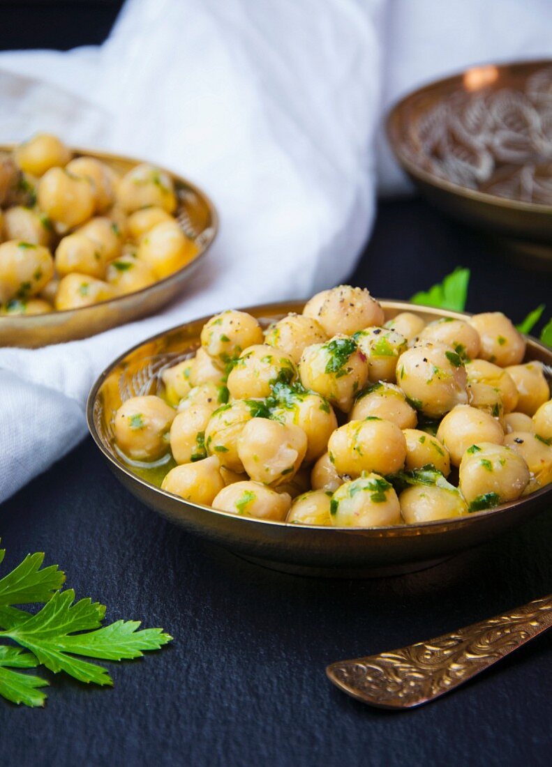 Chickpeas marinated in olive oil and fresh herbs plated in gold bowls