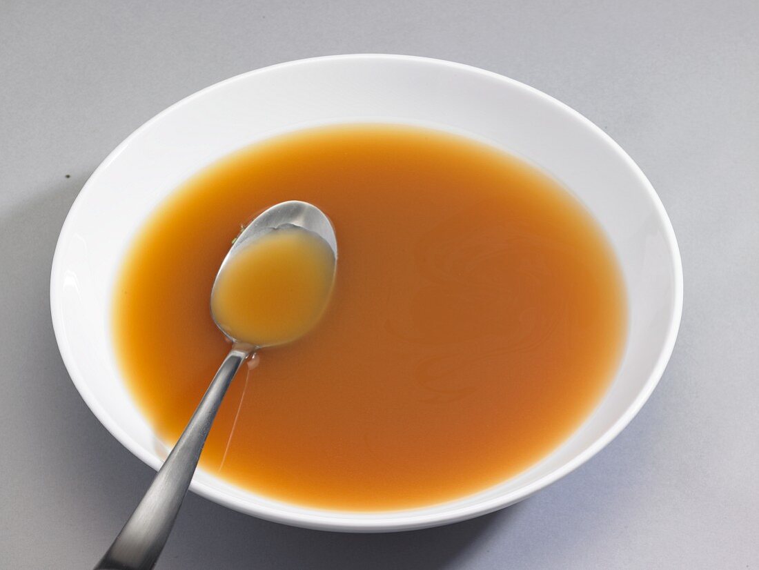 A bowl of chicken broth with a spoon