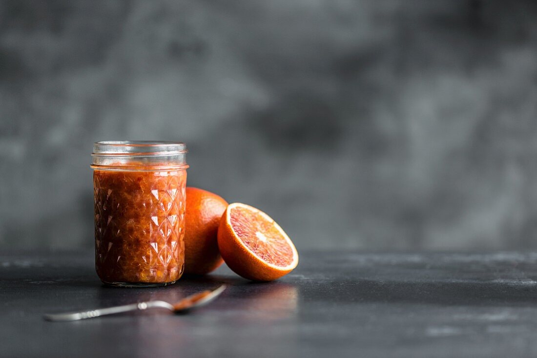 Blood orange compote in a glass in front of a grey background