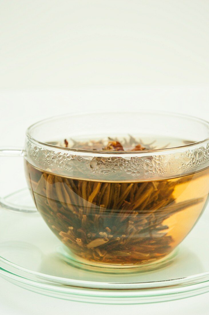 Weisser Tee mit Teeblume in Glastasse