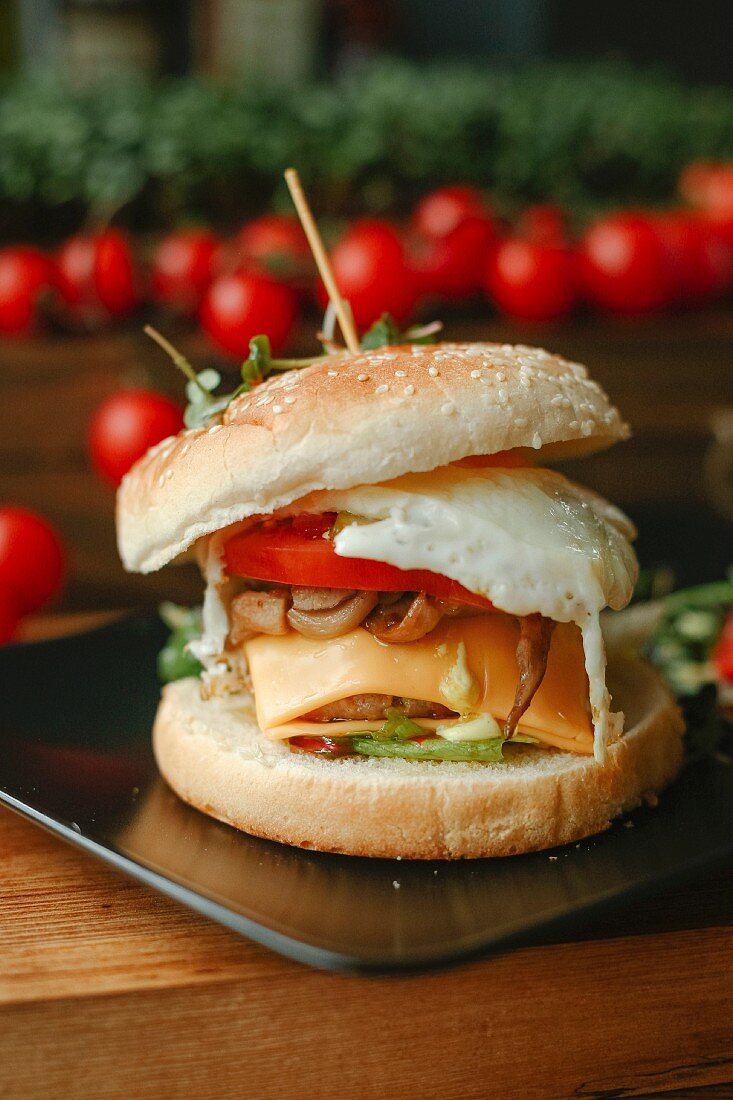 A cheeseburger with tomato and a fried egg