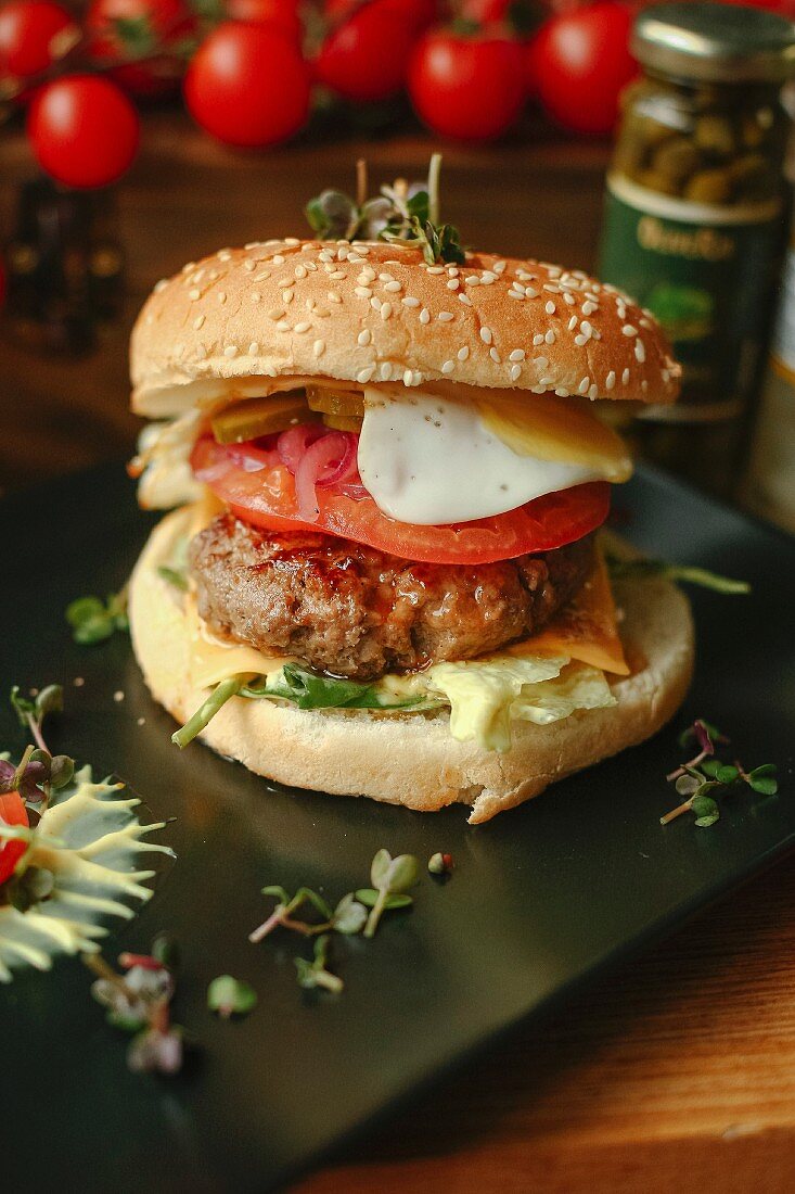 A cheeseburger with tomato and a fried egg