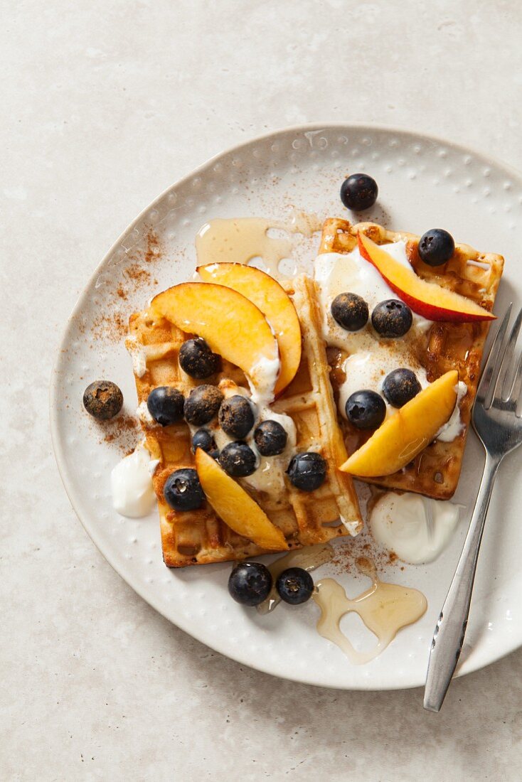 Belgian waffles with yoghurt, honey, blueberries and peach wedges