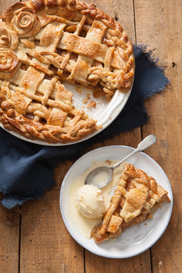 A slice of apple pie with vanilla ice cream on a plate