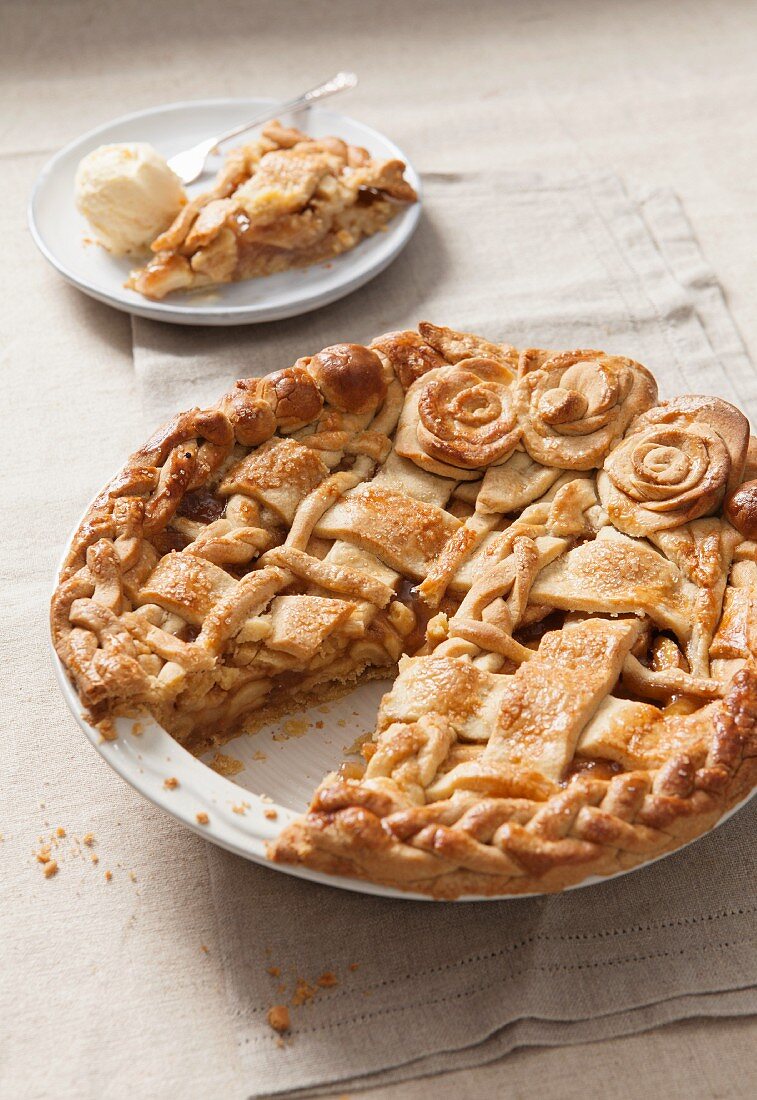Apple pie with a dough lattice and pastry roses in a baking dish, cut