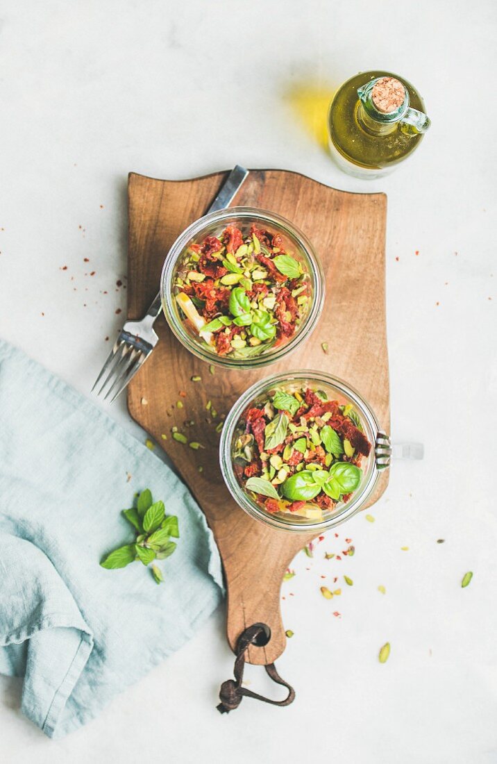 Veganer Quinoasalat im Glas mit Avocado, getrockneten Tomaten und Kräutern