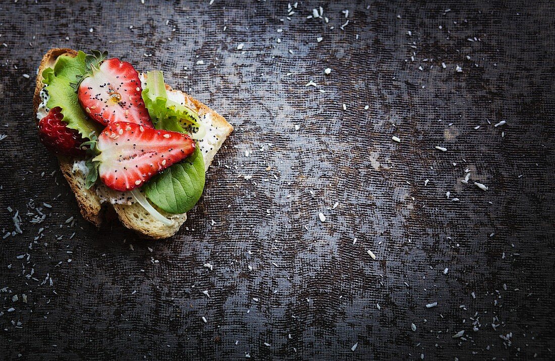 Brot belegt mit Frischkäse, Blattsalat und Erdbeeren (Aufsicht)
