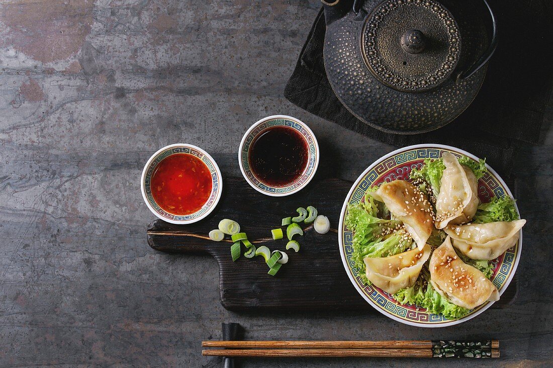 Gyozas potstickers on lettuce salad with sauces