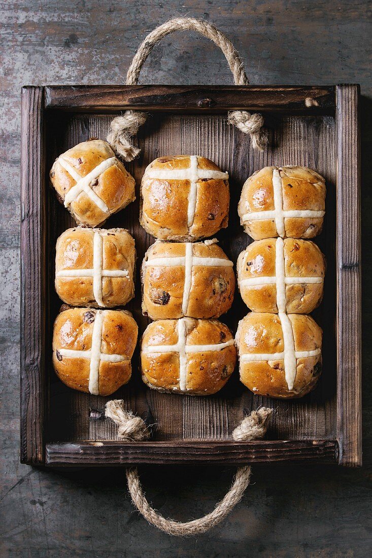 Hot cross buns in wooden tray over old texture metal background