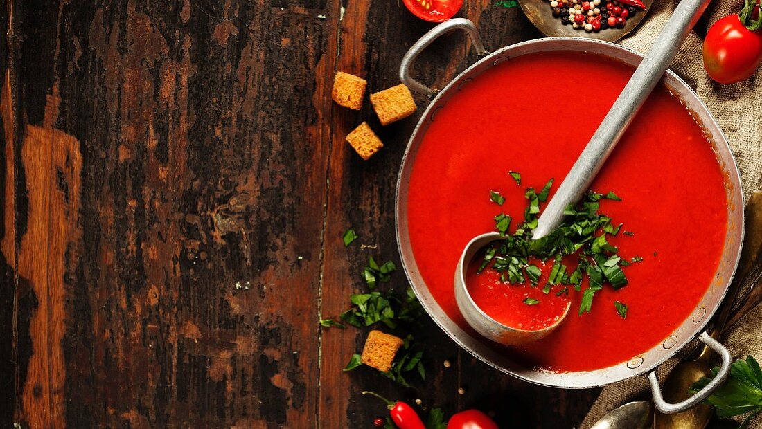Hausgemachte Tomatencremesuppe mit Suppenkelle im Kochtopf (Aufsicht)